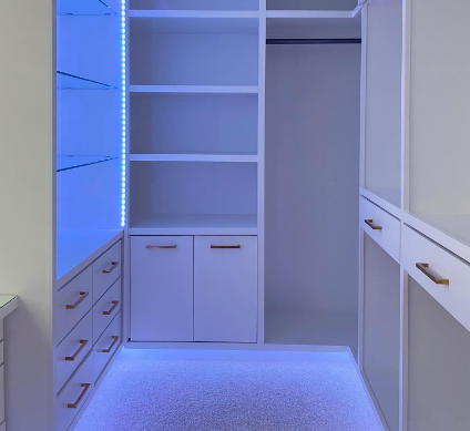 Luxury white closet with LED lighting, glass shelves, and gold handles, creating a modern and sophisticated design.